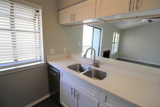 Kitchen with dishwasher, white cabinets, and light stone countertops | Image 4