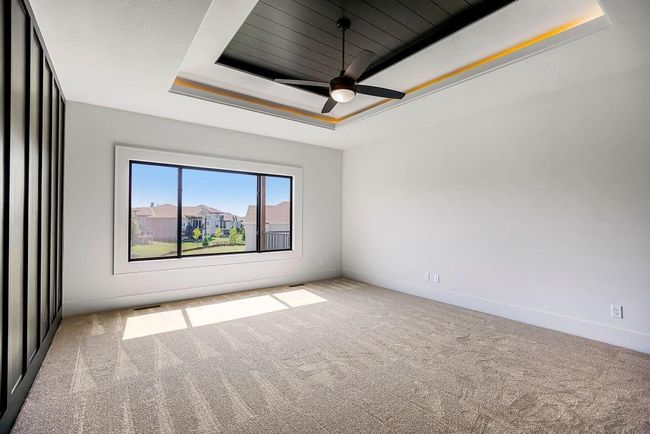 Carpeted empty room featuring a tray ceiling, baseboards, and ceiling fan | Image 20