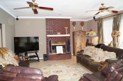 Living room with light tile patterned flooring, a brick fireplace, and ceiling fan | Image 3