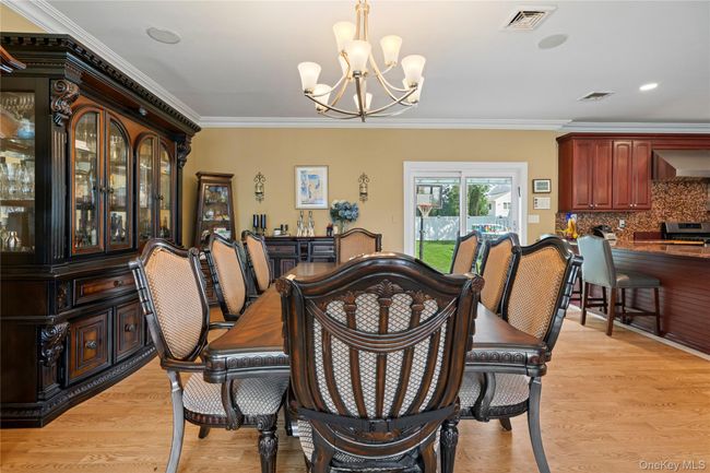 Dining area with ornamental molding, a chandelier, light wood-style flooring, a dry bar, and recessed lighting | Image 6
