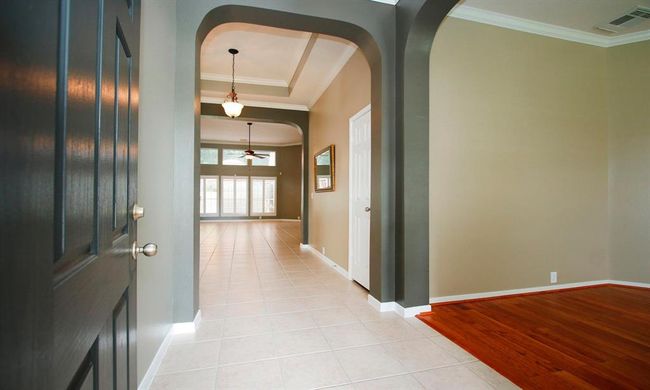 Upon entry you are greeted by a custom tray ceiling, crown molding and extended tile flowing through all main areas! The entry is adjoined by the home office on the right. | Image 4