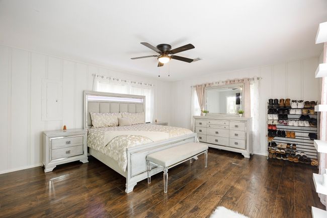 Bedroom with a decorative wall, a ceiling fan, and dark wood-style floors | Image 14