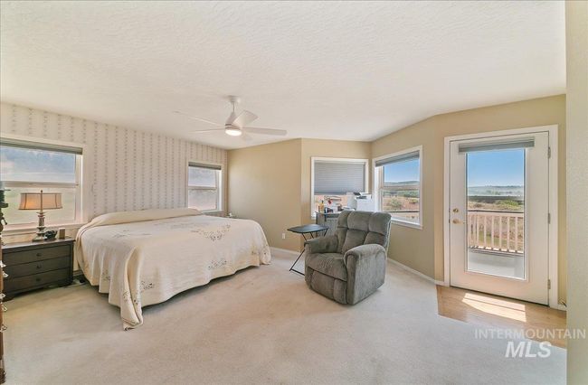 Bedroom featuring access to outside, multiple windows, ceiling fan, a textured ceiling, and light colored carpet | Image 32