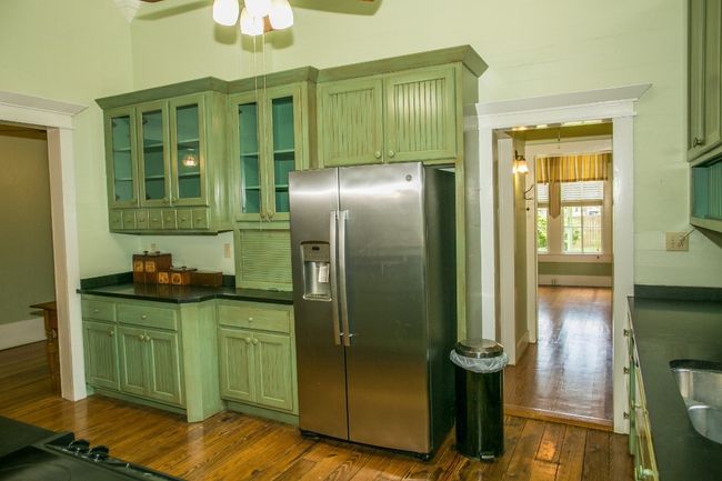 Kitchen featuring stainless steel refrigerator with ice dispenser, green cabinets, dark wood-type flooring, ceiling fan, and dark countertops | Image 13
