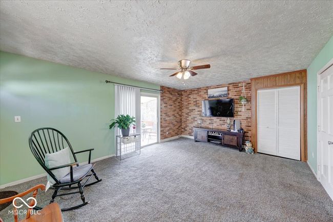 roomy living area with accent brick wall with a small closet | Image 21