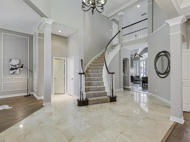 Entrance foyer featuring ornate columns, marble tiled floors, stairway, a towering ceiling, and a ceiling fan | Image 9