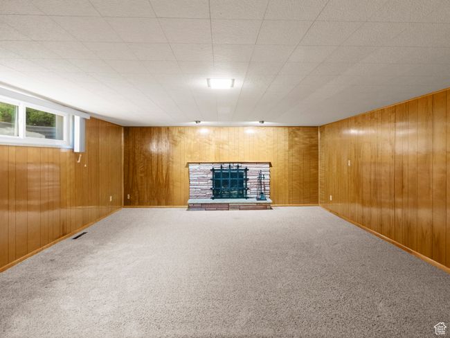 Great room with pristine wood paneling, a fireplace with raised hearth, and carpet flooring | Image 21