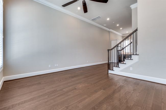 Living area featuring ornamental molding, a ceiling fan, wood finished floors, stairs, and plenty of natural light | Image 15
