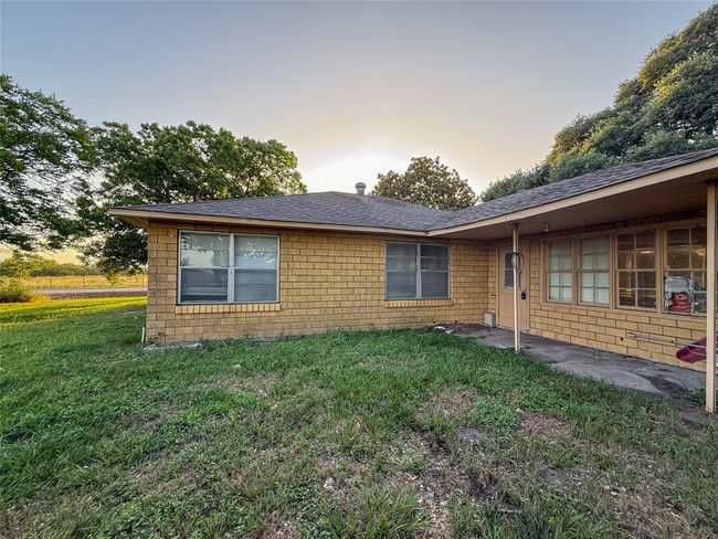 Charming single-story home with a cozy brick exterior, a small covered porch, and manicured bushes. Surrounded by lush greenery, it offers a serene and inviting atmosphere. | Image 19