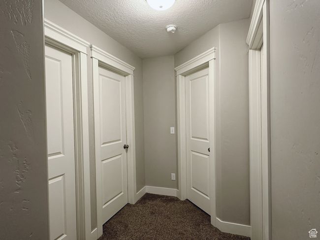 Hall featuring dark carpet and a textured ceiling | Image 19