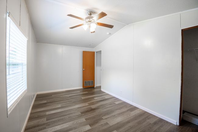 Unfurnished bedroom with wood finished floors, lofted ceiling, ceiling fan, and a closet | Image 22