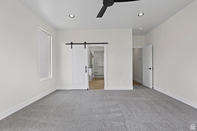 Unfurnished bedroom with baseboards, a barn door, and carpet flooring | Image 10