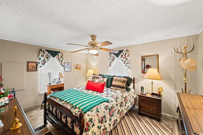 Bedroom with a textured ceiling, a ceiling fan, wood finished floors, and ornamental molding | Image 9