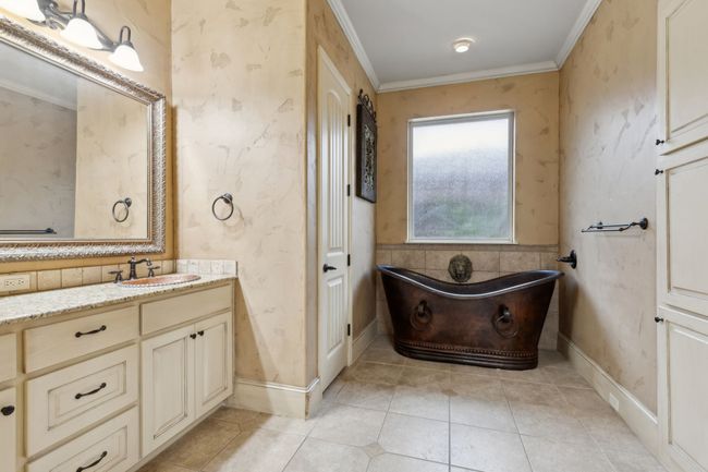 Full bathroom featuring vanity, a freestanding Copper bath tub, baseboards, ornamental molding, and tile patterned flooring | Image 14