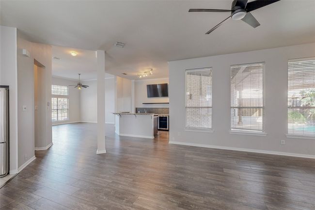 Unfurnished living room with a ceiling fan, dark wood-style flooring, and baseboards | Image 12