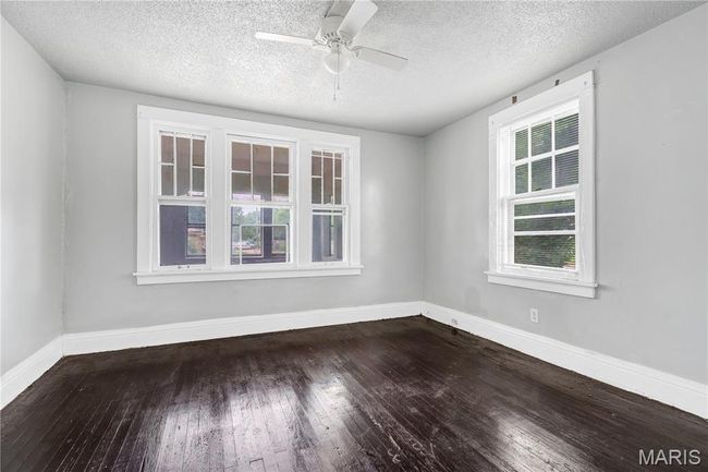 Empty room with hardwood / wood-style flooring, a textured ceiling, and a ceiling fan | Image 15