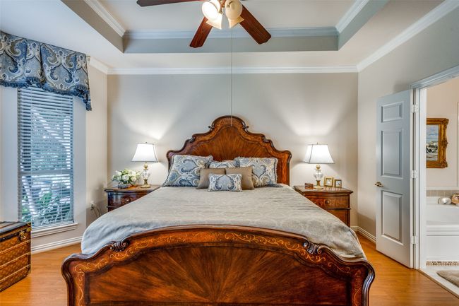 Bedroom featuring light wood finished floors, a raised ceiling, crown molding, and a ceiling fan | Image 17