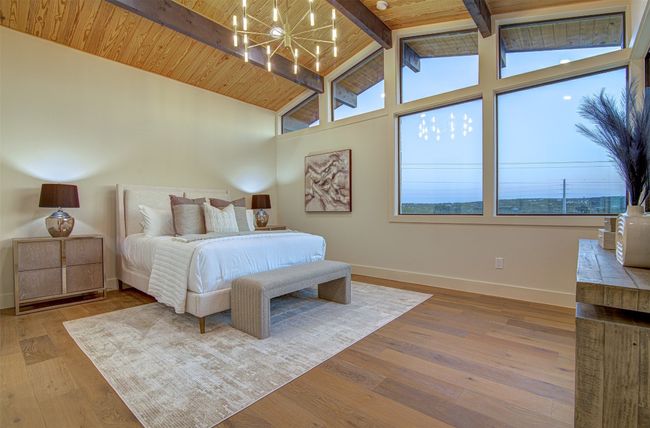 Bedroom with a chandelier, baseboards, multiple windows, wood finished floors, and high vaulted ceiling | Image 10