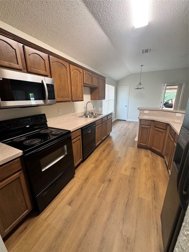 Kitchen with range, dishwasher, a sink, lofted ceiling, and light wood-style floors | Image 7