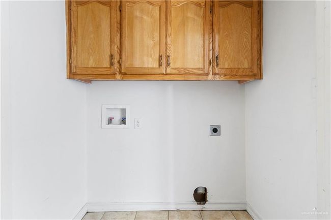 Laundry room with washer hookup, hookup for an electric dryer, cabinet space, and light tile patterned flooring | Image 17
