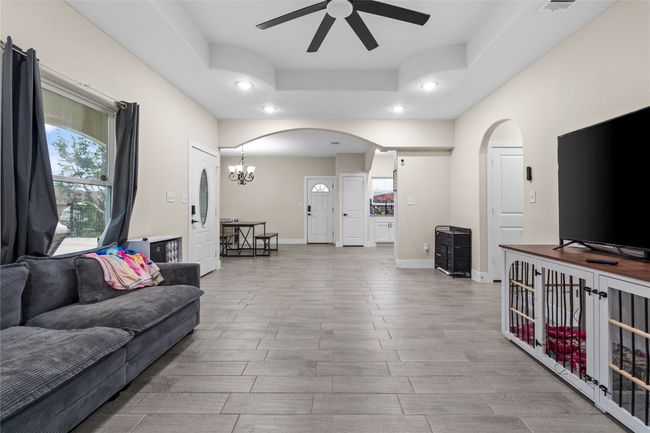 Living area featuring arched walkways, ceiling fan, recessed lighting, a raised ceiling, and wood finished floors | Image 14