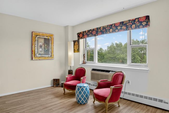Sitting room featuring baseboard heating, wood finished floors, and an AC wall unit | Image 24