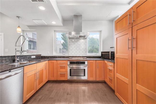Kitchen with stainless steel appliances, island exhaust hood, wood finished floors, recessed lighting, and dark stone countertops | Image 4