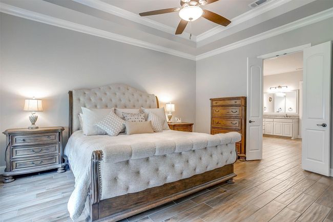 Bedroom featuring wood finish floors, ornamental molding, a tray ceiling, and ceiling fan | Image 29