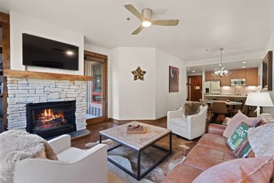 Living room featuring ceiling fan with notable chandelier, sink, hardwood / wood-style floors, and a stone fireplace | Image 3