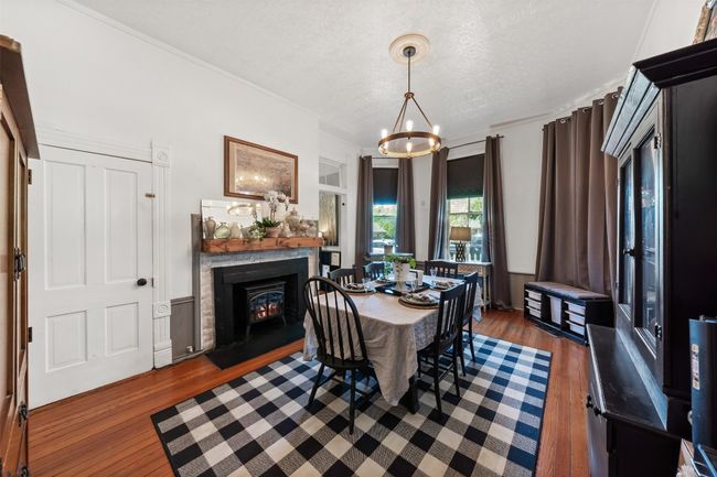 Dining area with a chandelier, wood finished floors, a textured ceiling, a lit fireplace, and crown molding | Image 13