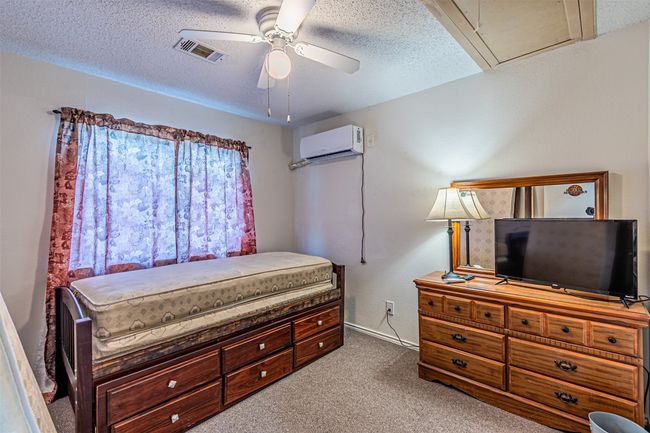 Carpeted bedroom with a wall mounted AC, a ceiling fan, and a textured ceiling | Image 23