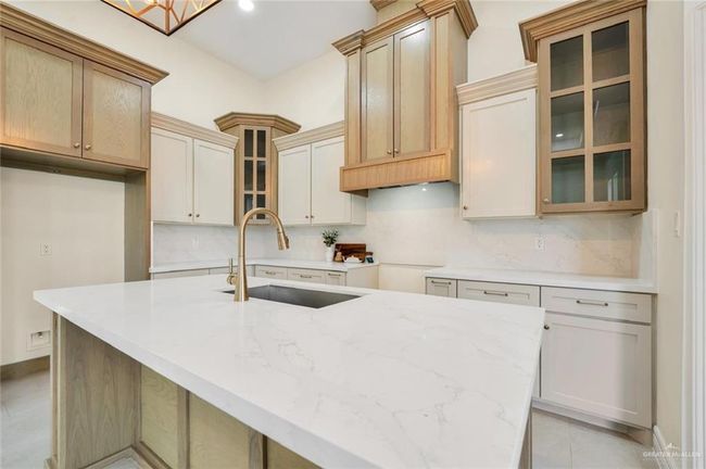Kitchen with a sink, tasteful backsplash, a kitchen island with sink, light stone countertops, and recessed lighting | Image 10