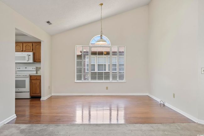 Unfurnished dining area featuring lofted ceiling, wood finished floors, and baseboards | Image 13