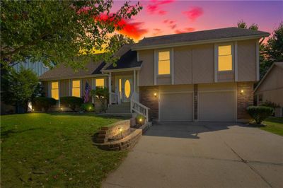 Split level home featuring a yard and a garage | Image 1