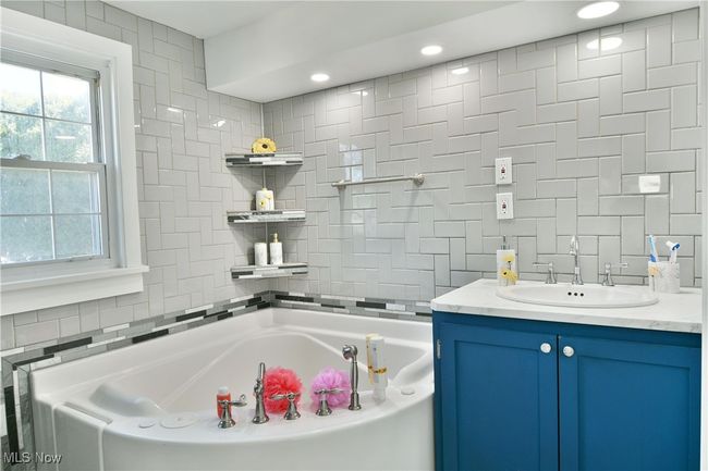 Full bathroom with tile walls, a garden tub, and vanity | Image 28