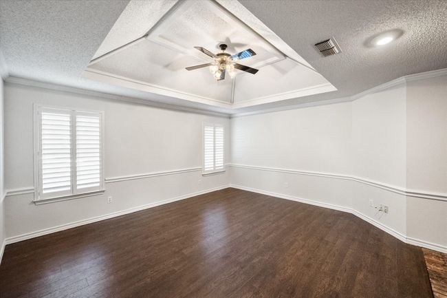 This living room has handsome engineered wood floors, chair railing, a wall of windows with plantation shutters and an inset ceiling with fan. The interior of the home was painted in April 2025. | Image 8