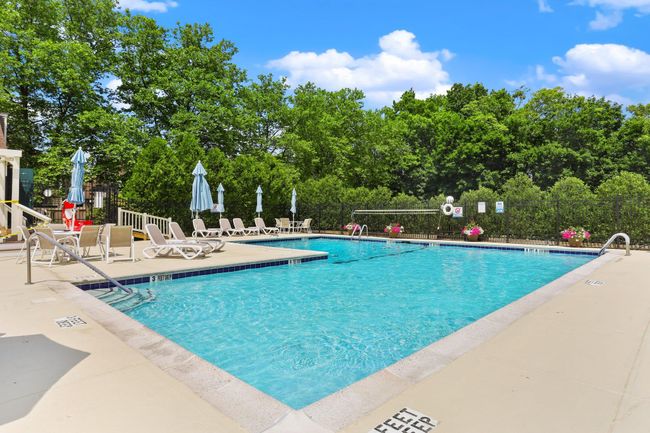 Community pool featuring a patio area and view of scattered trees | Image 38
