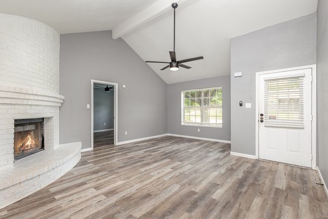Unfurnished living room with a ceiling fan, a fireplace, beam ceiling, wood finished floors, and baseboards | Image 8