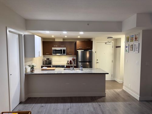 Kitchen featuring a peninsula with a stone-finish countertop, stainless steel appliances, recessed lighting, and wood-finish flooring | Card Image