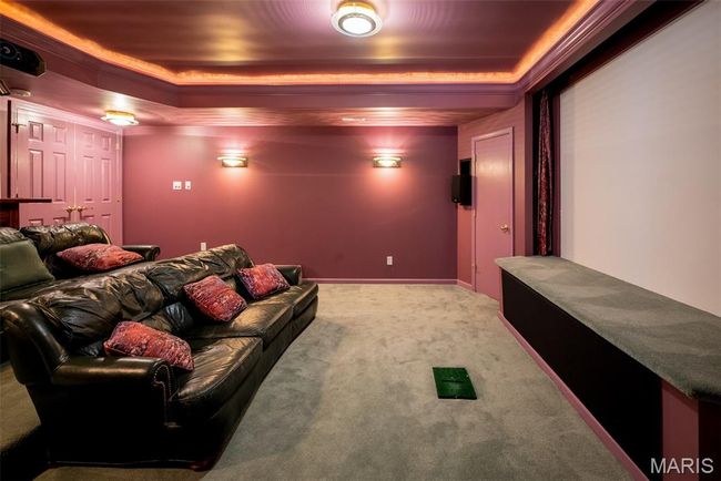 Carpeted home theater room with a tray ceiling | Image 44