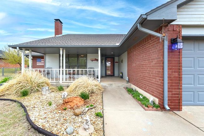 Property entrance with covered porch, a chimney, brick siding, a shingled roof, and a garage | Image 6