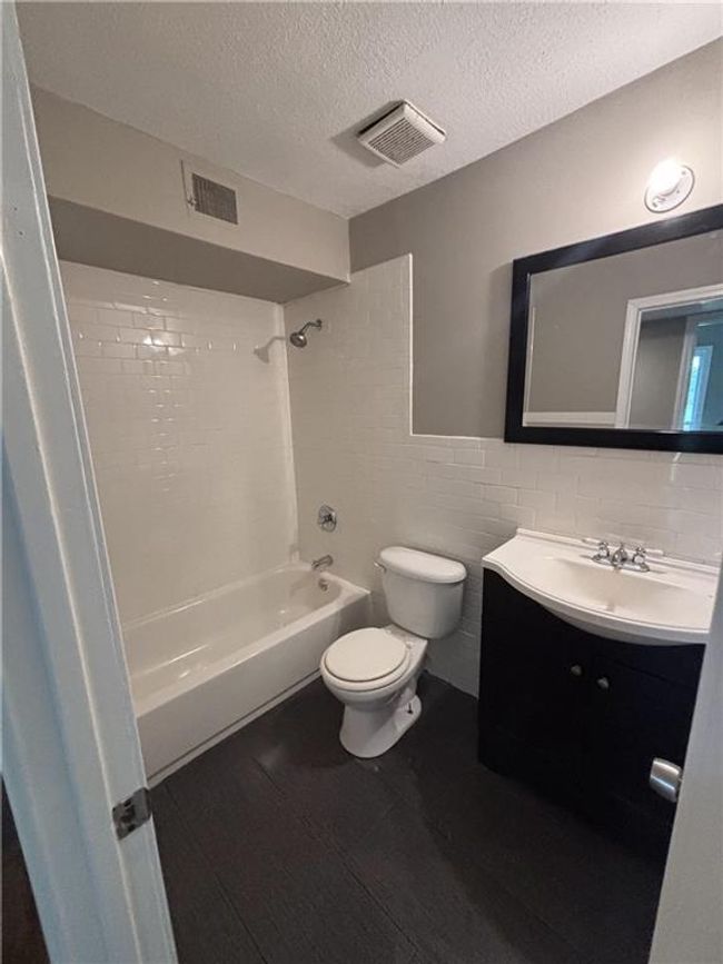 Bathroom with wood finished floors, visible vents, toilet, and tub / shower combination | Image 26