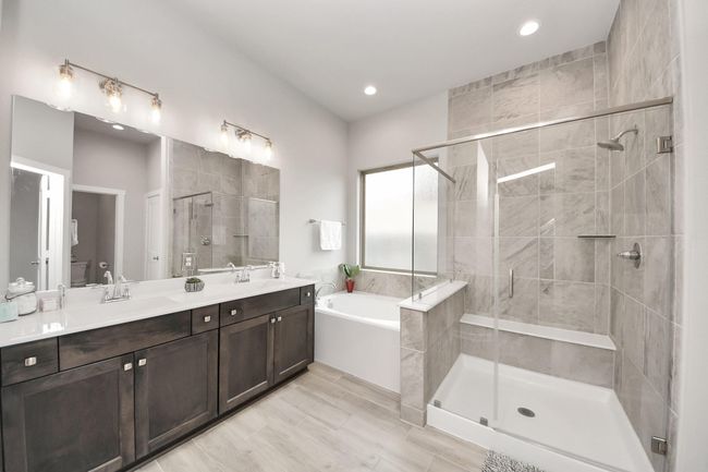 Luxurious primary bath featuring double vanities, soaking tub, and separate glass shower. | Image 27