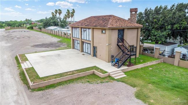 Rear view of property with stucco siding, a chimney, stairway, and a tile roof | Image 5