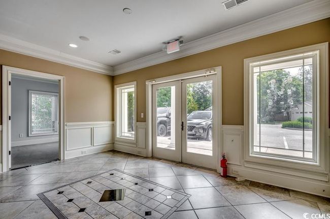 Doorway to outside with french doors, crown molding, a wainscoted wall, a decorative wall, and inlaid floor details | Image 5