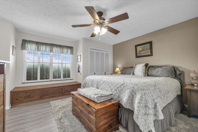 Bedroom with a textured ceiling, a closet, light wood finished floors, and ceiling fan | Image 23