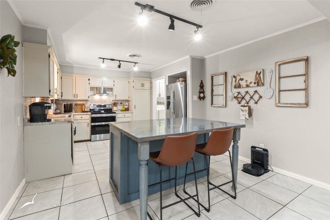 Kitchen with track lighting, crown molding, range hood, and stainless steel appliances | Image 8