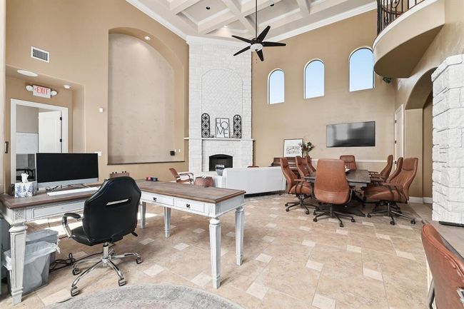 Office space featuring coffered ceiling, a ceiling fan, a fireplace, a high ceiling, and visible vents | Image 7
