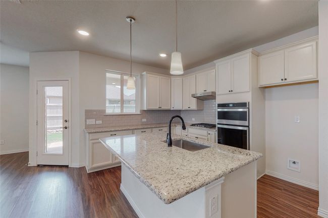 Kitchen with a sink, appliances with stainless steel finishes, dark wood-type flooring, under cabinet range hood, and backsplash | Image 7