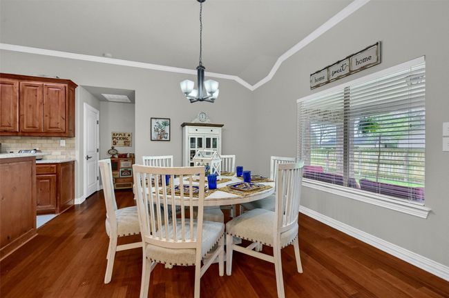 Dining area featuring crown molding, vaulted ceiling, baseboards, dark wood finished floors, and a notable chandelier | Image 12